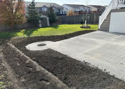 A backyard cement patio with fresh dirt ready for seeding and landscaping.