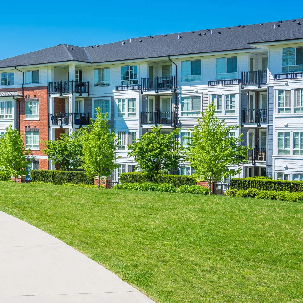 Apartment building with concrete walkway and well-maintained grounds