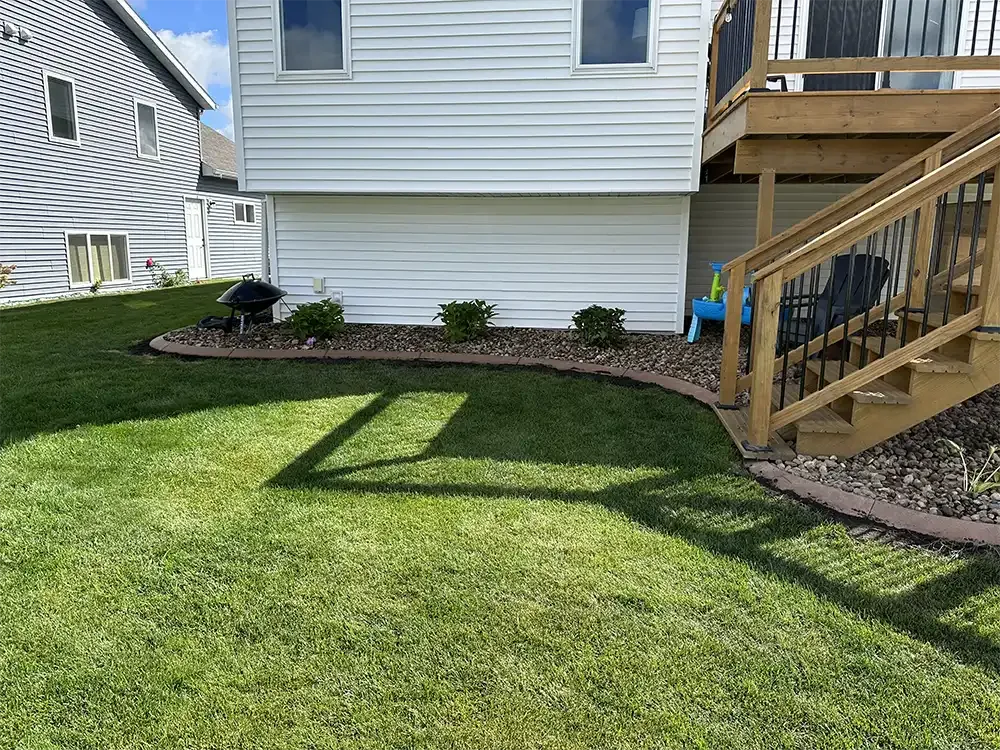 Back yard with beautiful landscaping, deck, and concrete curbing